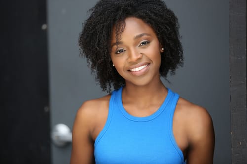 Headshot of woman with curly black hair and bright blue tank top.